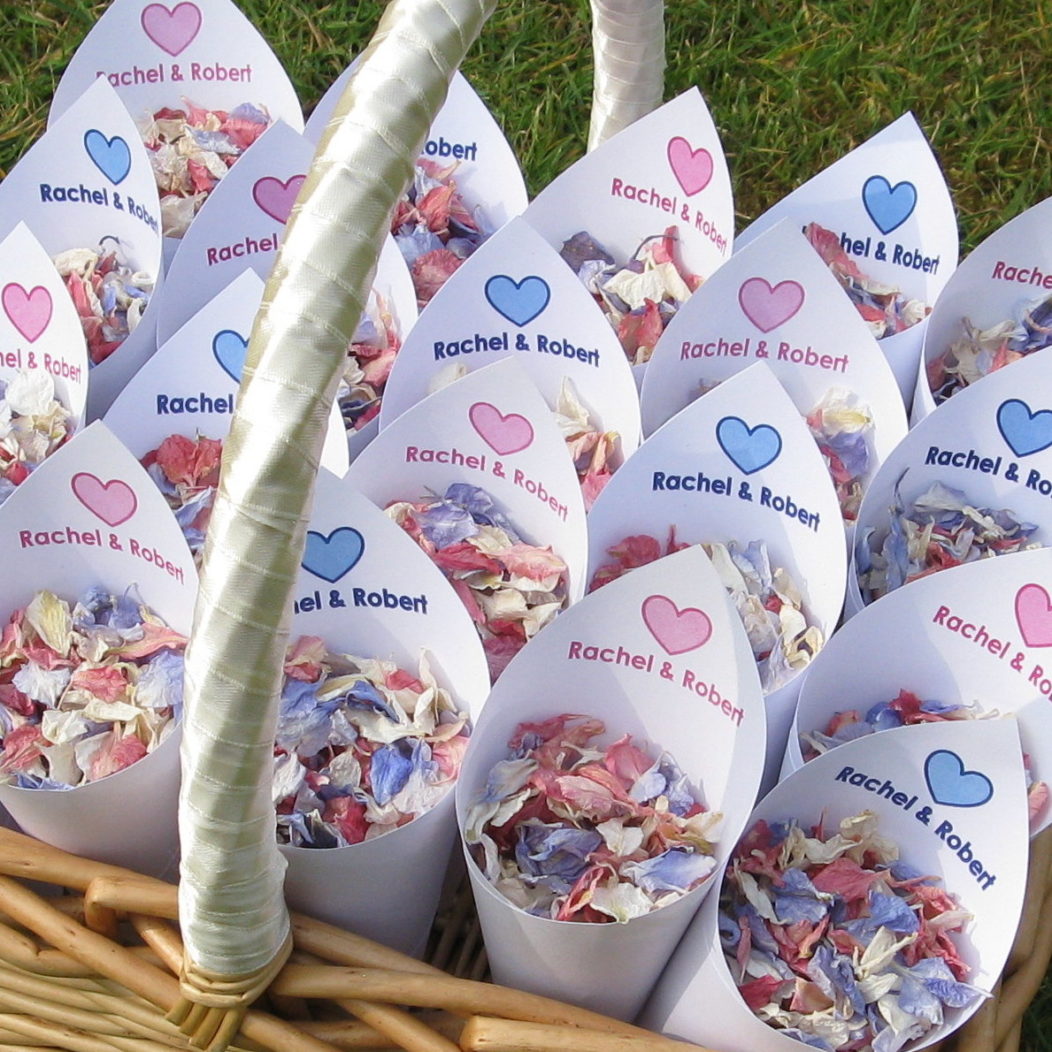 Personalised Love Heart Confetti Cones filled with Raspberry, Ivory and Azure Blue Delphinium Petals in a Rectangular Basket with a cream ribbon handle