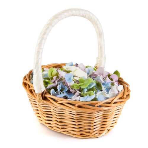 A wicker basket with a cream ribbon covered handle. The basket is full of multicoloured hydrangea petals.