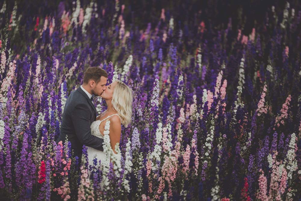 bespoke confetti from the confetti flower field Brdie and groom kissing in the colours of the confetti flower field