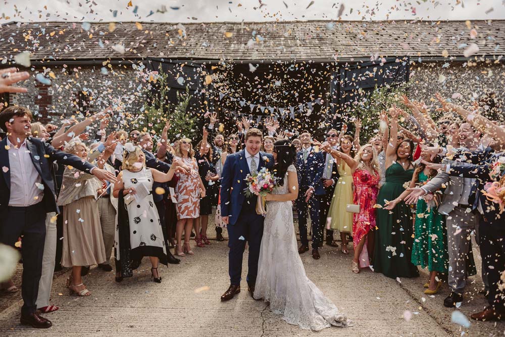 The 2019 winning confetti moment photograph showing a bride and groom surrounded by a big circle of their wedding guests, and the sky is full of real flower petal confetti.