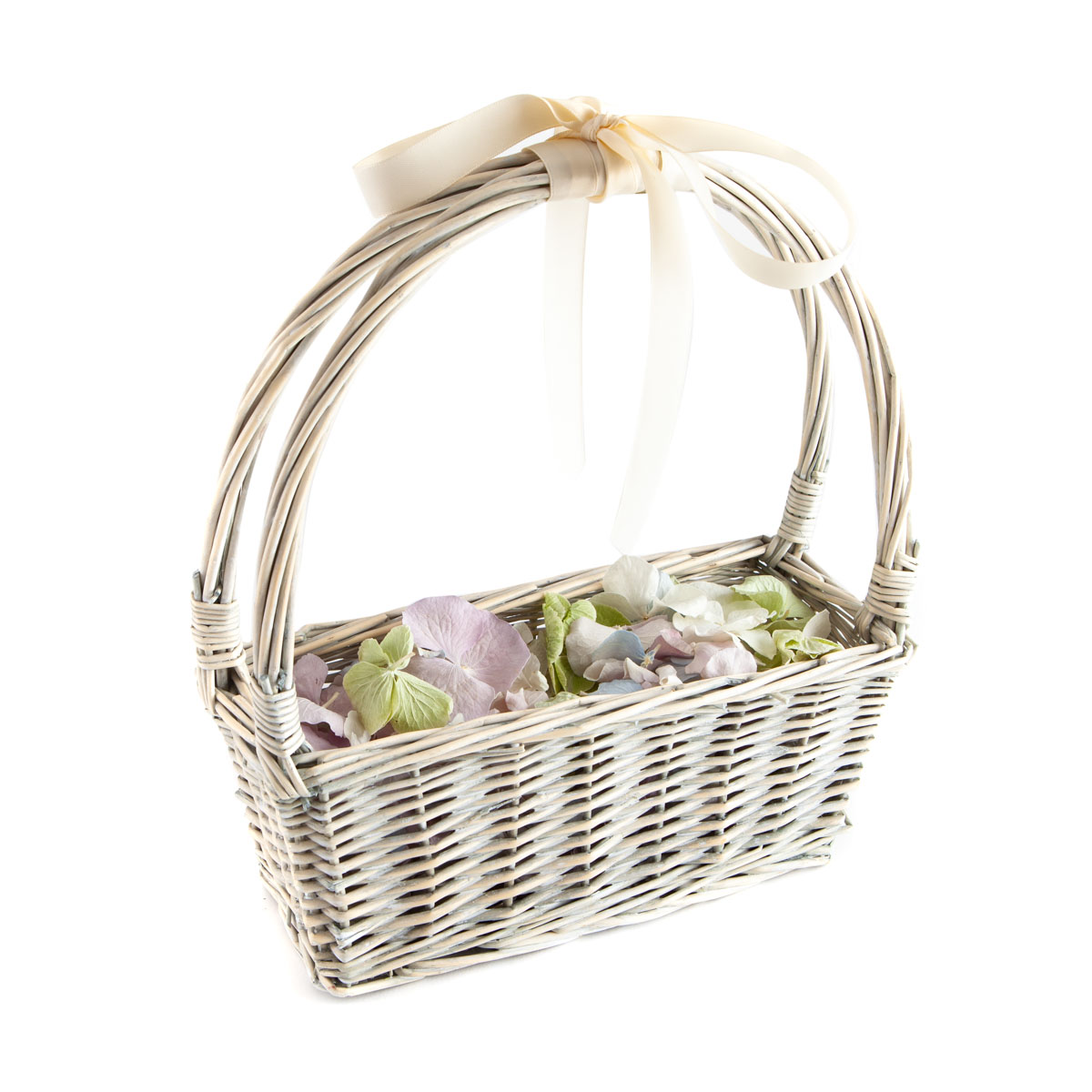A narrow white basket of Hydrangea Petal Confetti. The petals are lilac, blue and green and the basket has a ribbon bow tied on the handle.